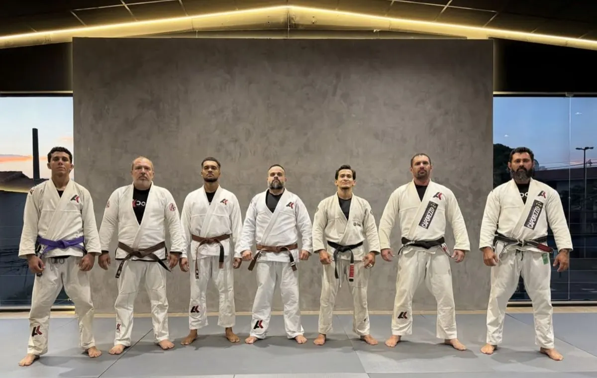 Professores e alunos graduados do instituto, de kimono, lado a lado no tatame