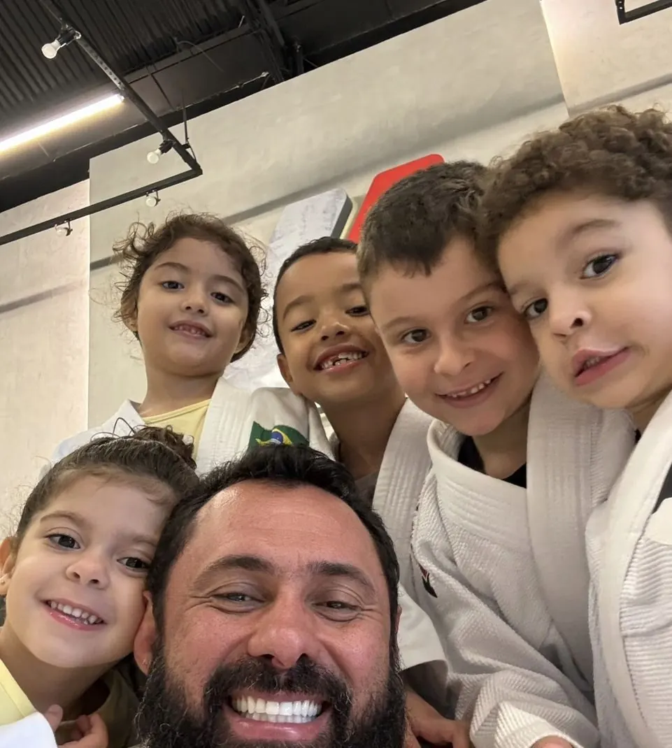 Professor sorridente com crianças de kimono em uma selfie
